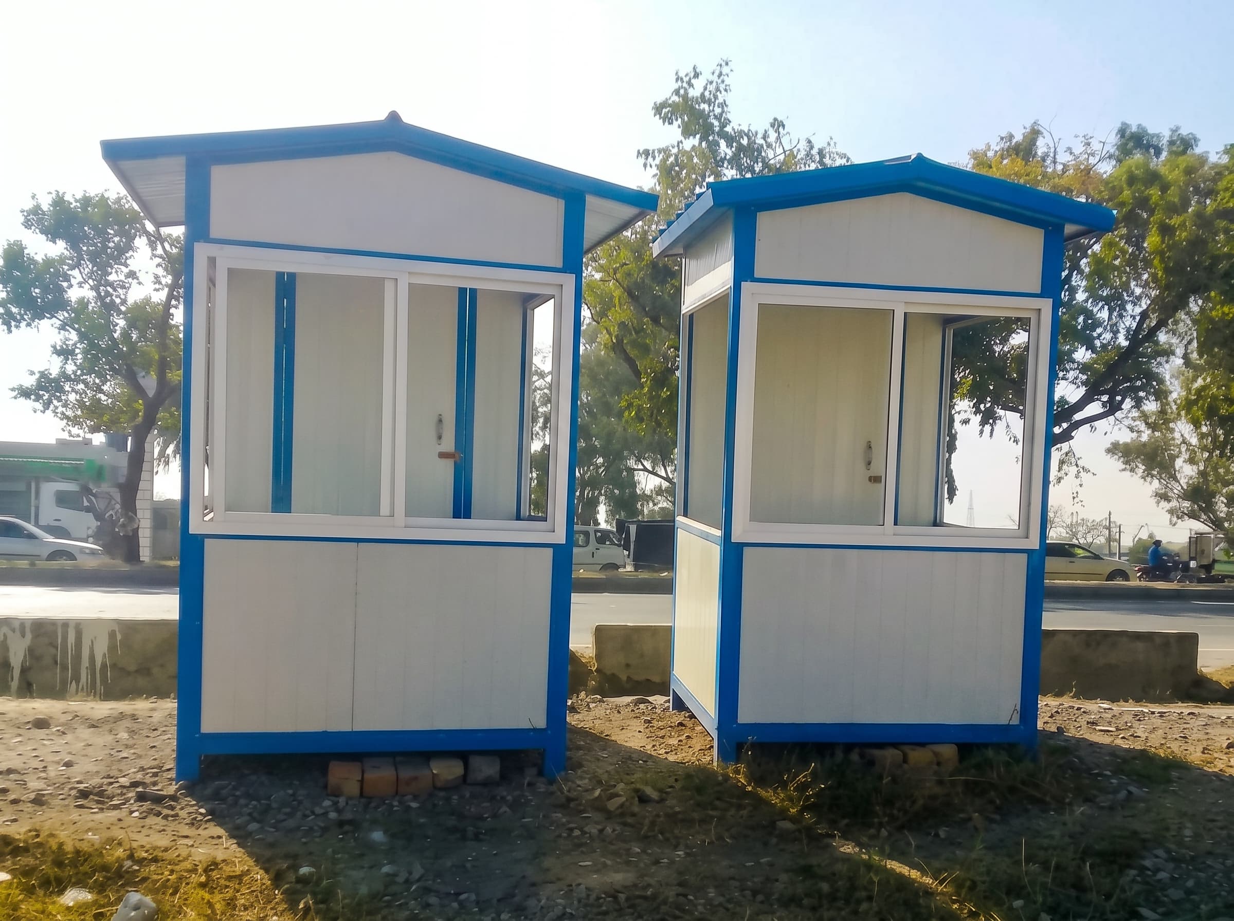 Two white steel guard cabins with blue frames