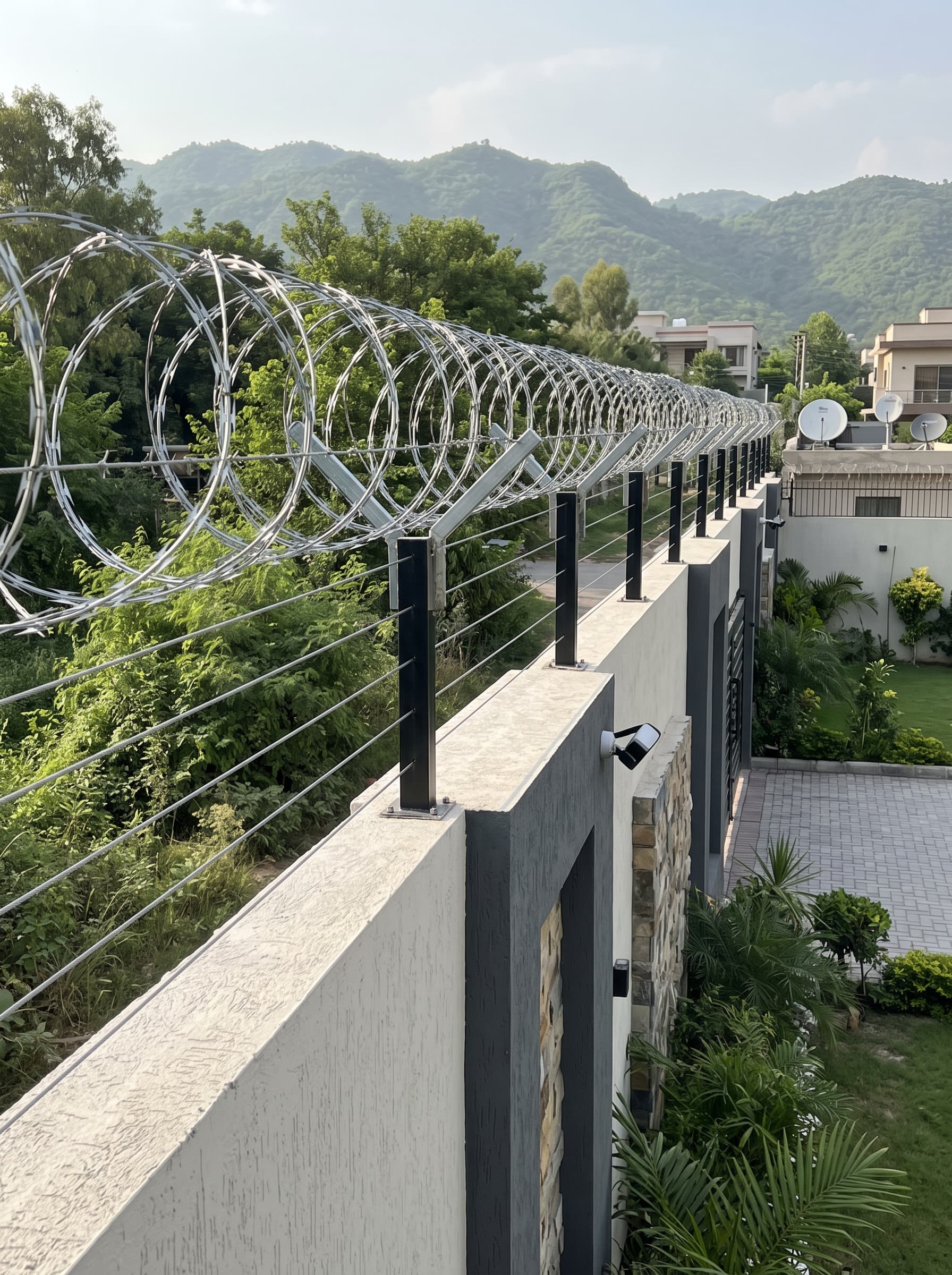 Razor wire coils on steel brackets along the top of a boundary wall
